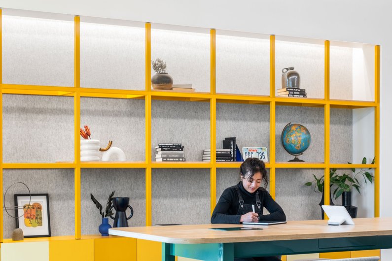 grey felt lines the walls behind shelf in office